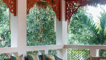 Un área de estar al aire libre con techo, mobiliario de madera y paneles decorativos rojos.