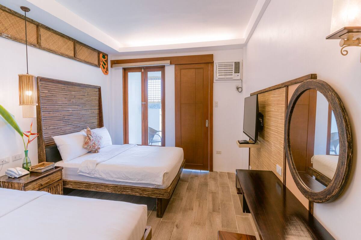 Une chambre d’hôtel avec un lit, une table de chevet, une lampe et un grand miroir.
