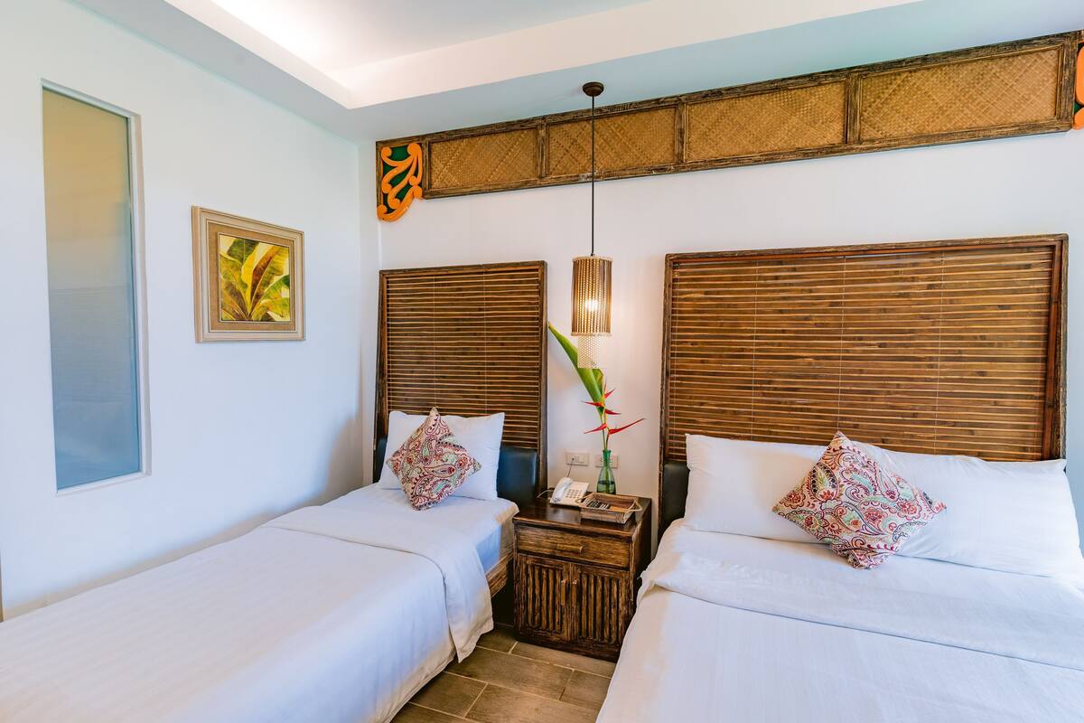 Une chambre d’hôtel avec deux lits, une table de chevet, une lampe et une œuvre d’art accrochée au mur.