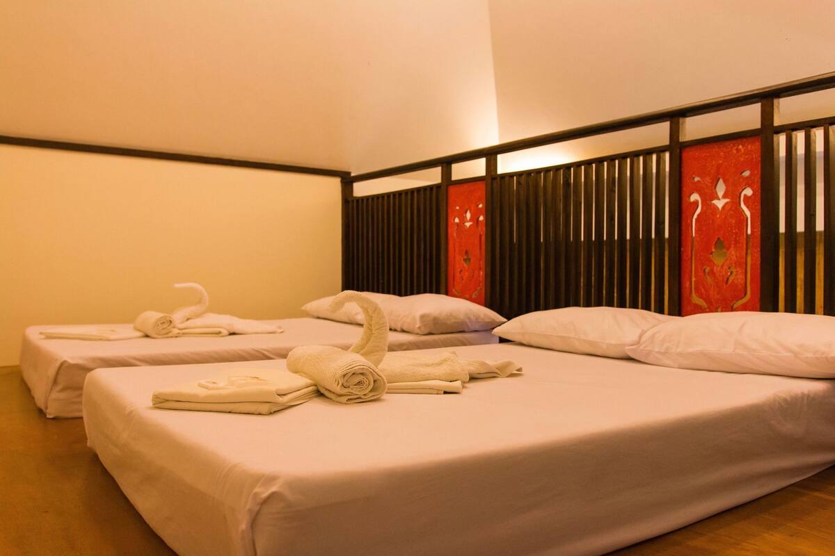 Une chambre d’hôtel avec deux lits, chacun agrémenté de serviettes et d’oreillers soigneusement pliés.