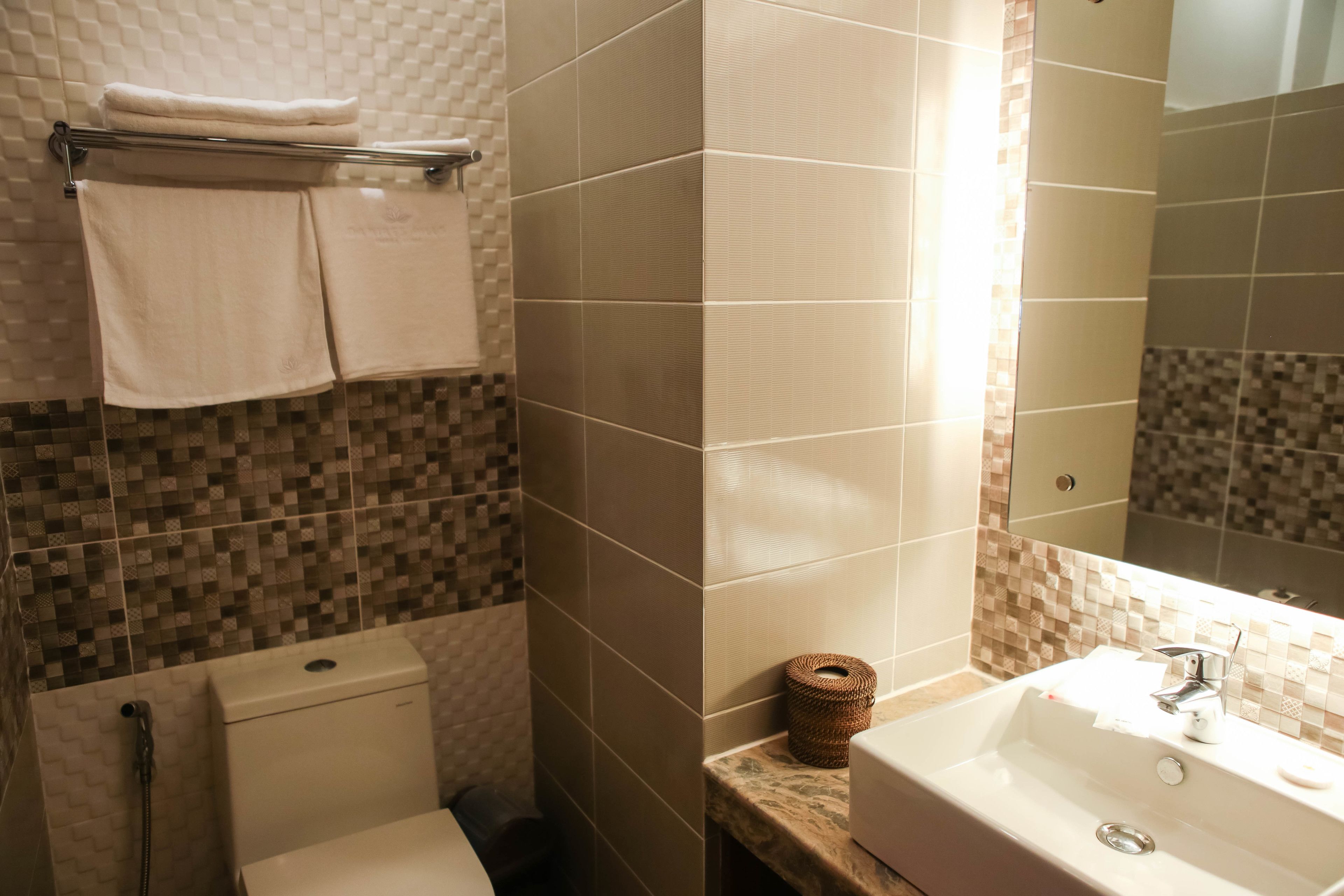 A bathroom with a toilet, a sink, and a towel rack with folded towels.