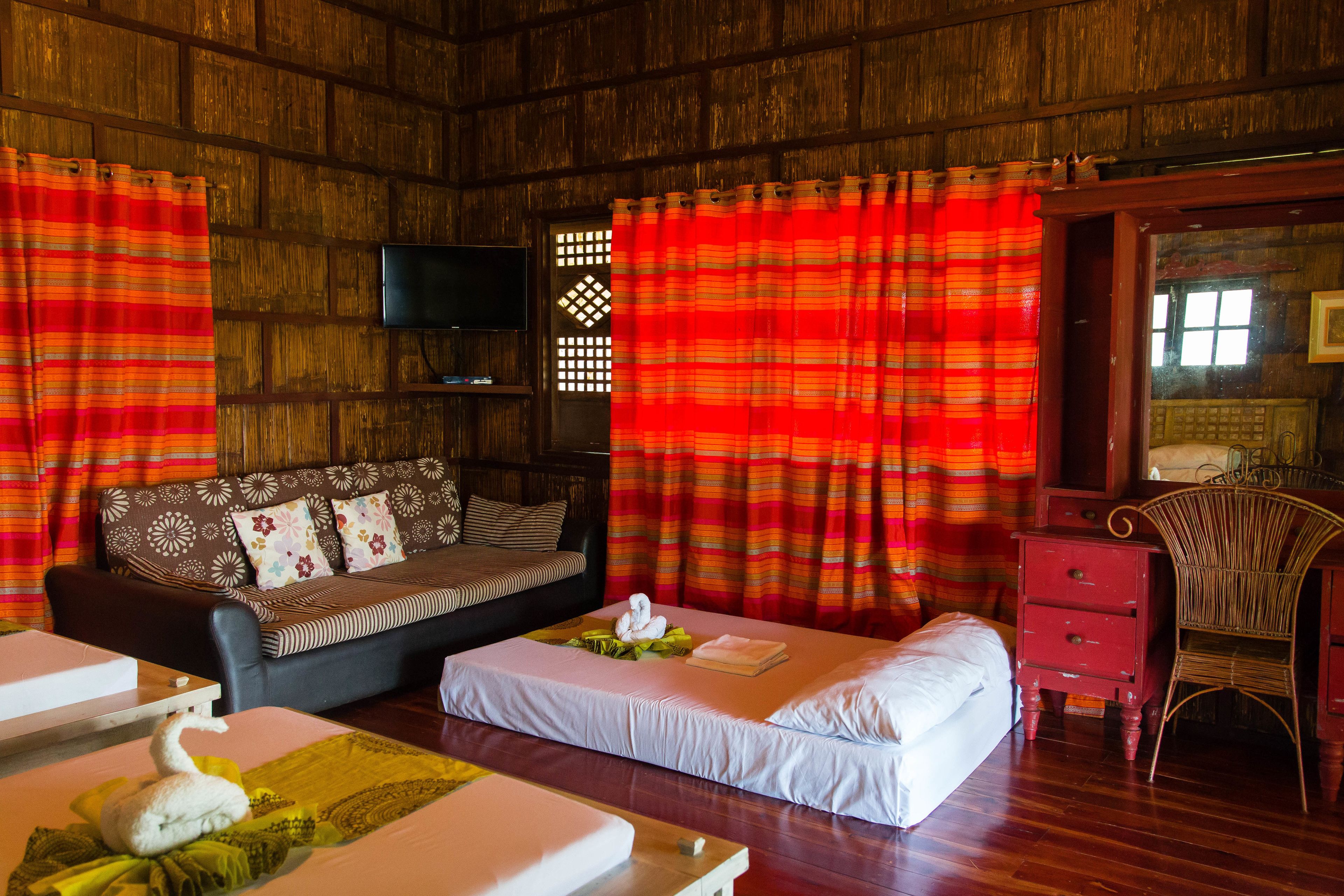 A room with a wooden wall, a sofa, a bed, a chair, and a TV.
