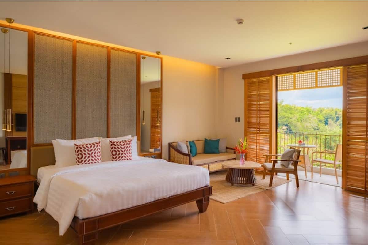 Une chambre spacieuse avec un grand lit, un canapé et un balcon offrant une vue agréable.