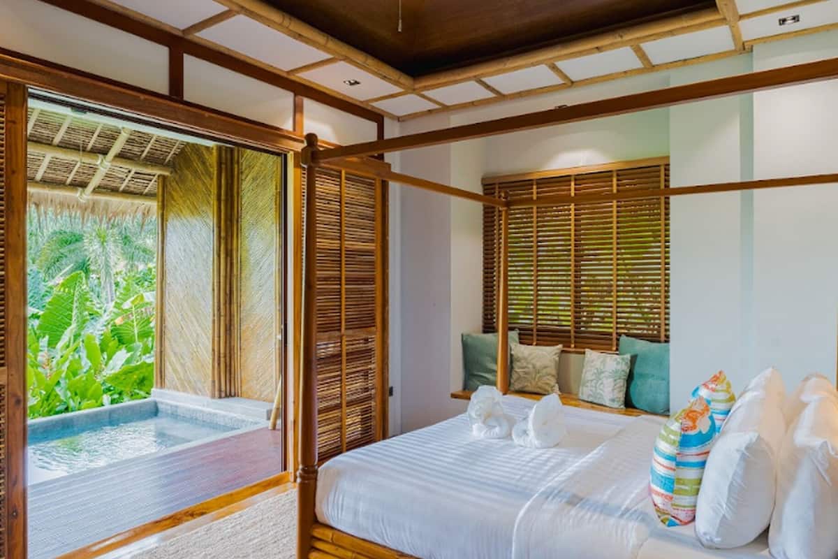 Une chambre avec un lit, une fenêtre avec des stores et une vue sur la verdure.
