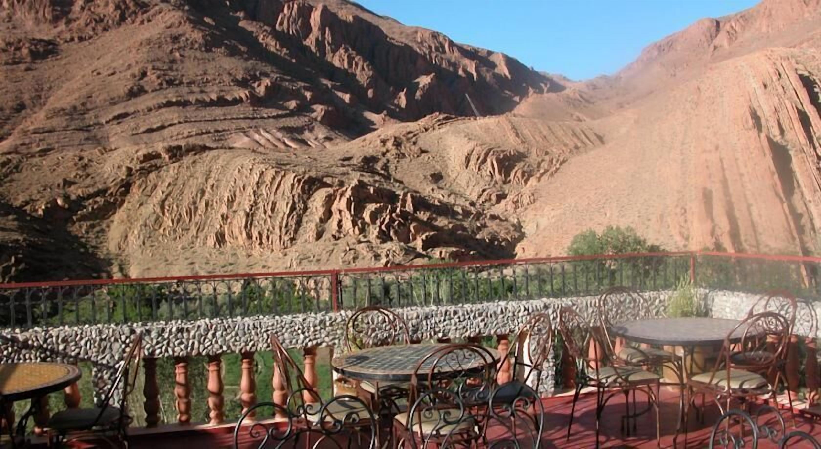 Een terras met een tafel en stoelen, met uitzicht op een bergachtig landschap.