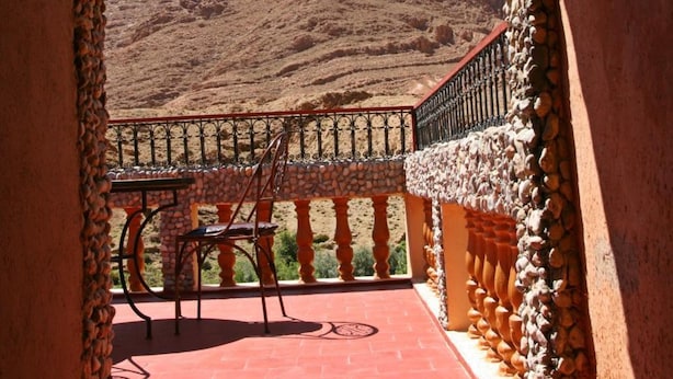 A balcony with a stone archway, a red tiled floor, and a view of a mountainous landscape. - Maison d'hôtes Valentine (Toudgha El Oulia)