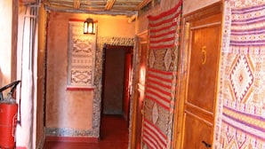 A corridor with patterned rugs, a wooden door, and a hanging lantern. - Maison d'hôtes Valentine (Toudgha El Oulia)