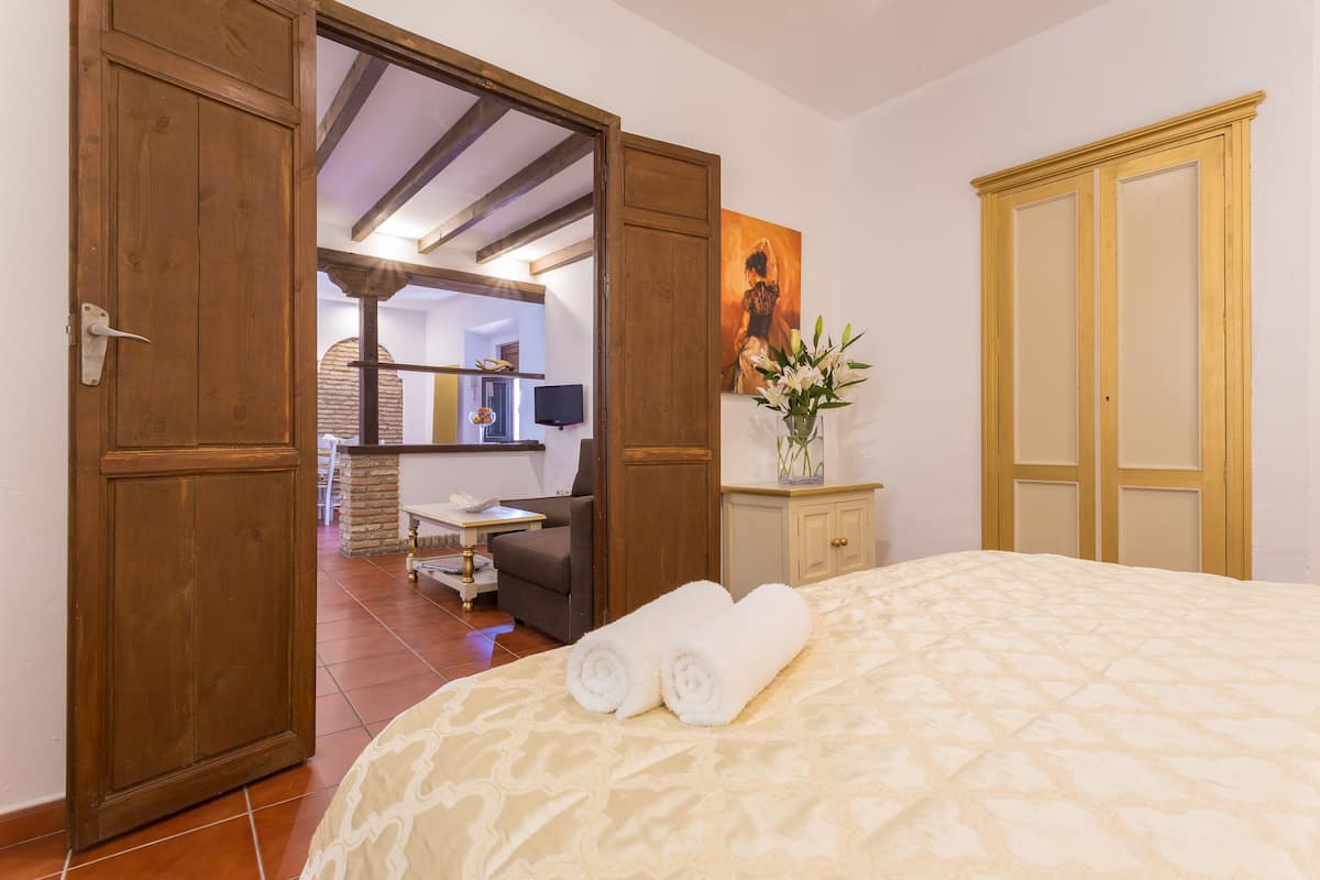 Una habitación de hotel con una cama, un armario de madera, un escritorio con una silla y un cuadro en la pared.