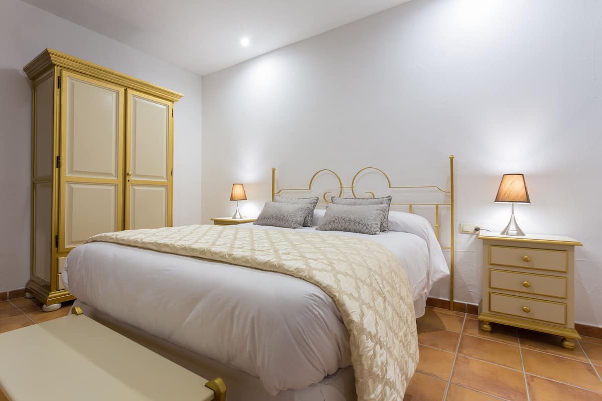 Un dormitorio con cama, mesitas de noche y un armario.