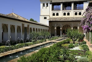 Un patio con fuente, arcos y un edificio con balcones.