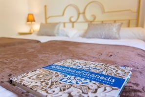 Una cama con un libro titulado "Alhambra de Granada" encima.