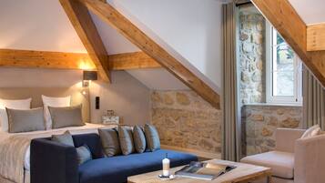 Una habitación acogedora con una cama, un sofá azul, una mesa de centro de madera y una pared de piedra.