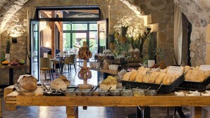Een ontbijtbuffet met brood, gebak en fruit in een kamer met ruwe stenen muren.