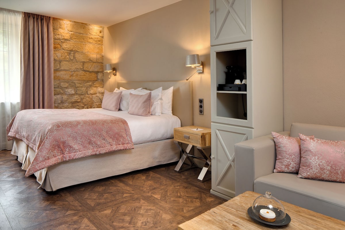 Een slaapkamer met een groot bed, een nachtkastje, een houten salontafel en een bank.