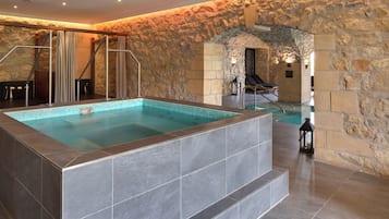 Suuri sisäuima-allas, jonka seinät ja lattia ovat kivestä, ja jonka ympärillä on kivinen holvikaari.