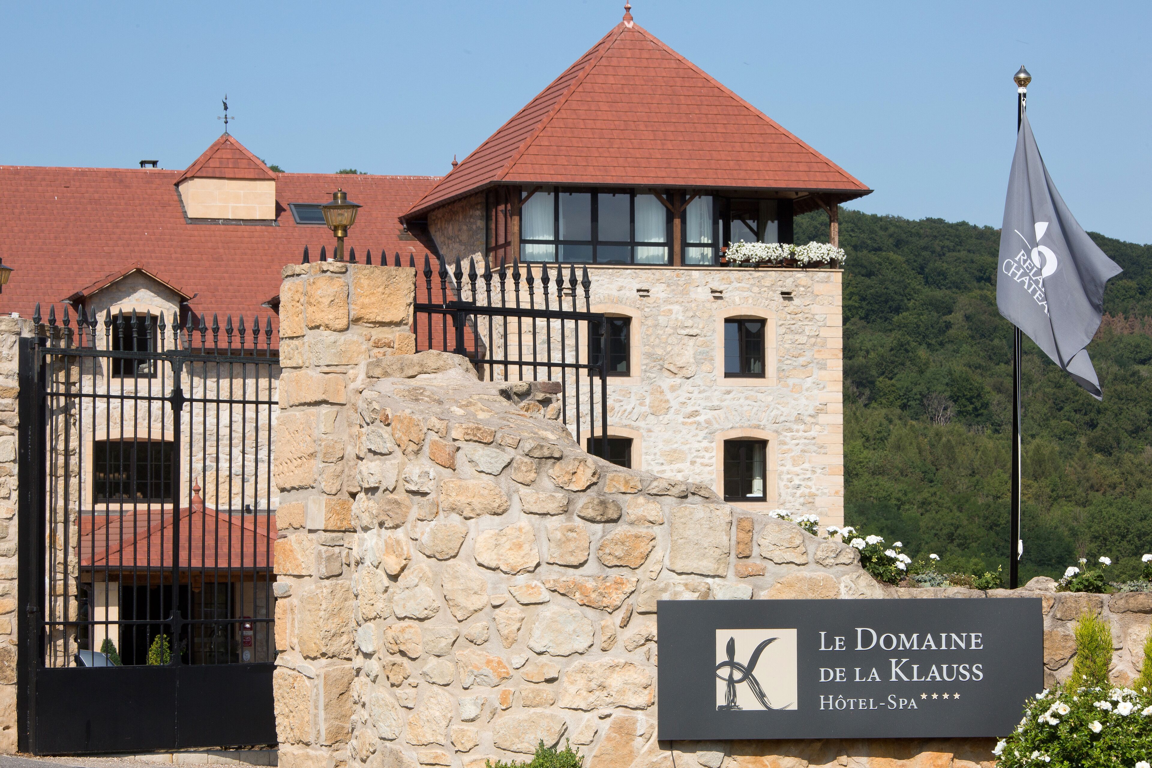 A stone building with a red roof and a sign for Le Domaine de la Klaus.