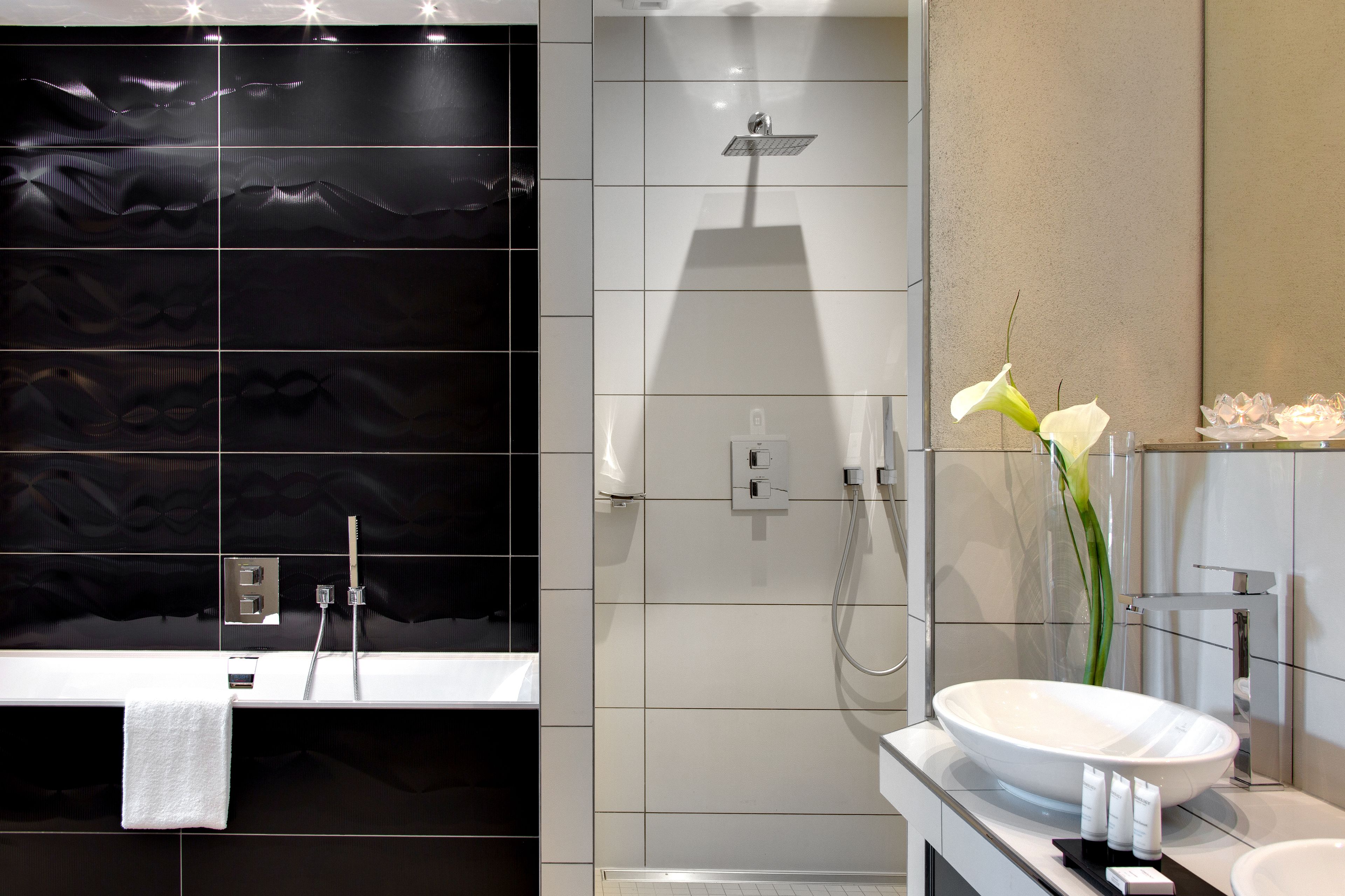 A modern bathroom with a large bathtub, a separate shower area, and a vanity with a sink and mirror.
