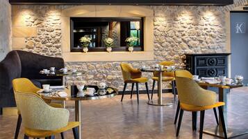 A modern dining area with stone walls, a fireplace, and a view of the outdoors.