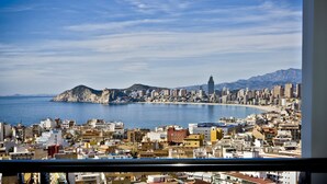 A coastal cityscape with a prominent mountain and a tall building in the distance. - Madeira Centro (Benidorm)