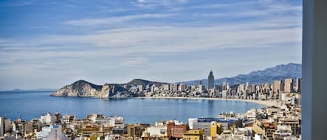 A coastal cityscape with a prominent mountain and a tall building in the distance.