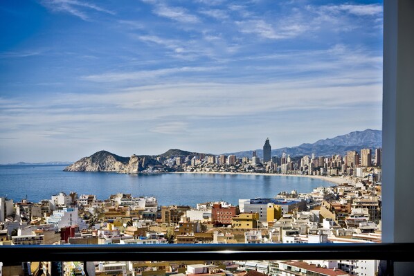 A coastal cityscape with a prominent mountain and a tall building in the distance. - Madeira Centro (Benidorm)