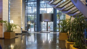 A spacious lobby with a glass entrance, modern architecture, and potted plants. - Madeira Centro (Benidorm)