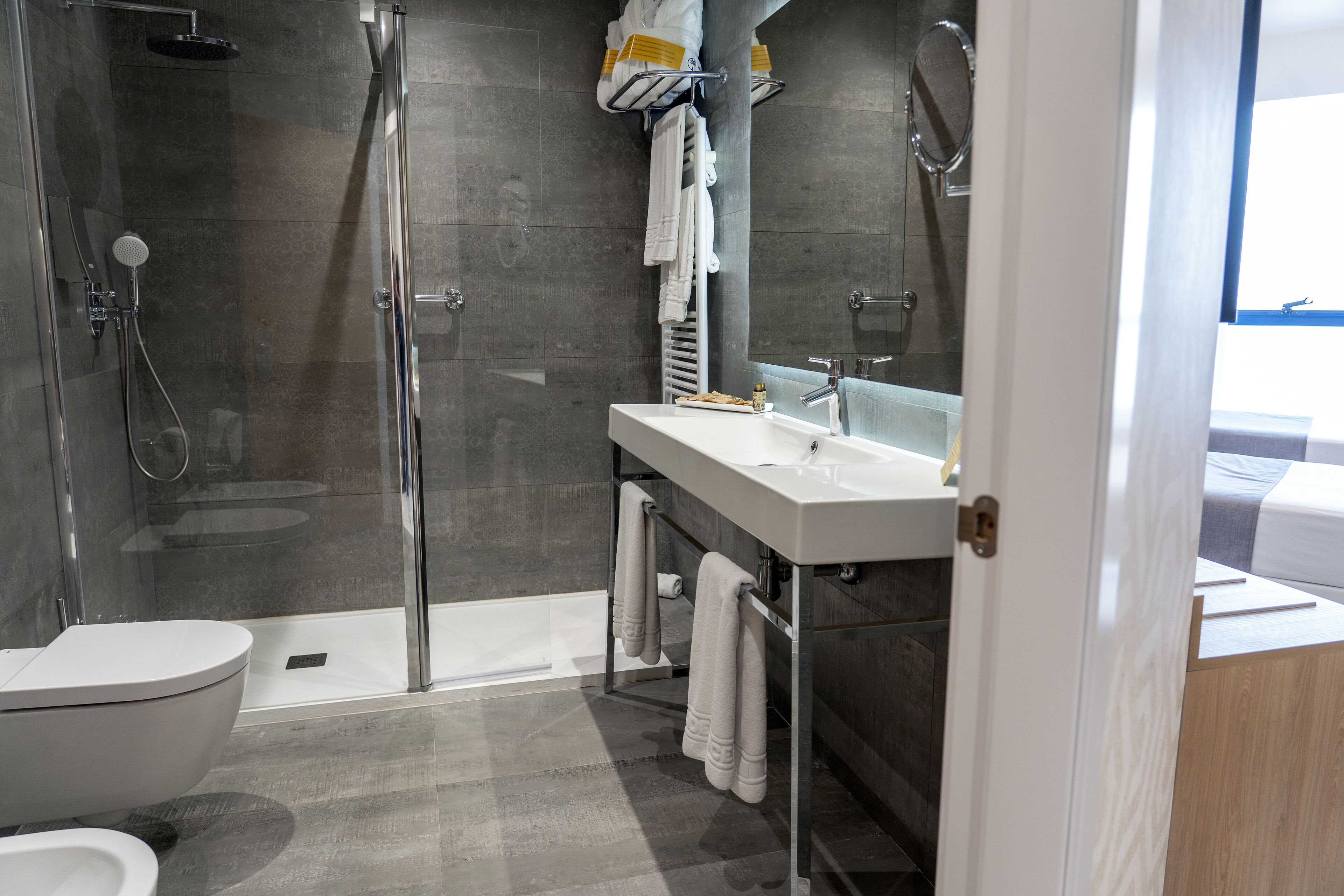 A modern bathroom with a glass-enclosed shower, a white sink, and a mirror above it.