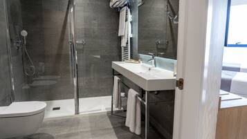 A modern bathroom with a glass-enclosed shower, a white sink, and a mirror above it.