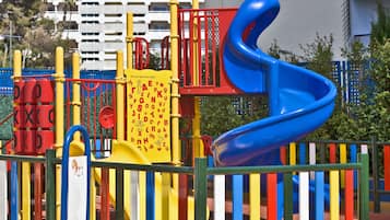 Une aire de jeux avec un toboggan bleu et des structures de jeu jaunes et rouges.