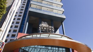 Un hotel moderno con ingresso curvo, facciata in vetro e un cartello ben visibile.
