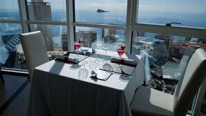 Tavolo apparecchiato per due con vista sul mare e sugli edifici.