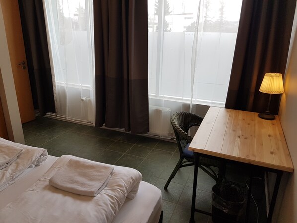 Una habitación de hotel con una cama, una mesa de madera, una silla y una ventana con cortinas.