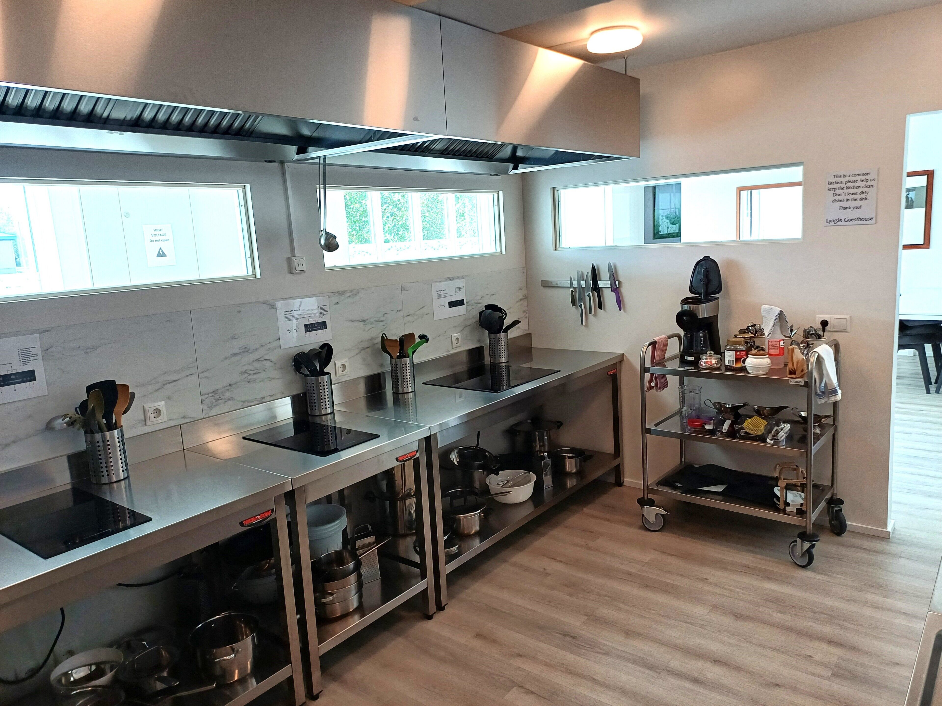 Una cocina moderna con electrodomésticos de acero inoxidable, una isla central y un carro con utensilios básicos.