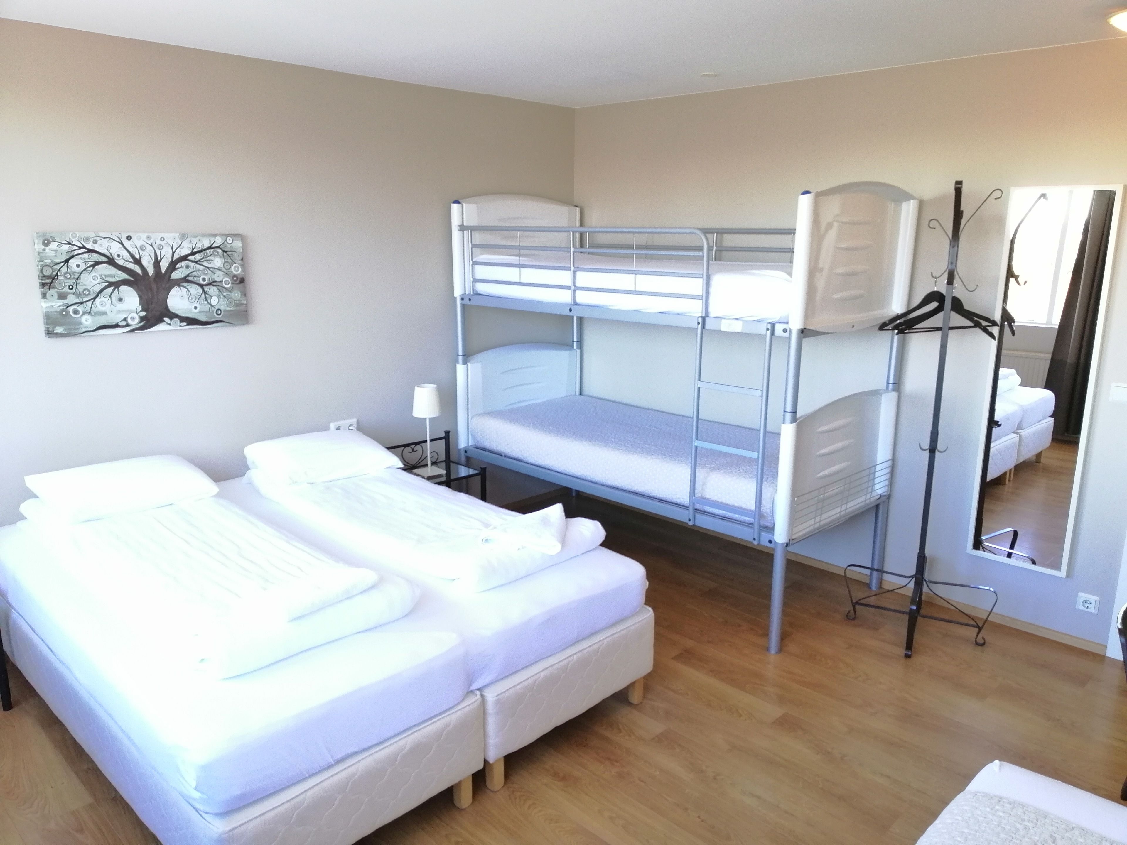 Una habitación con literas, un escritorio, una silla, una lámpara y un espejo.