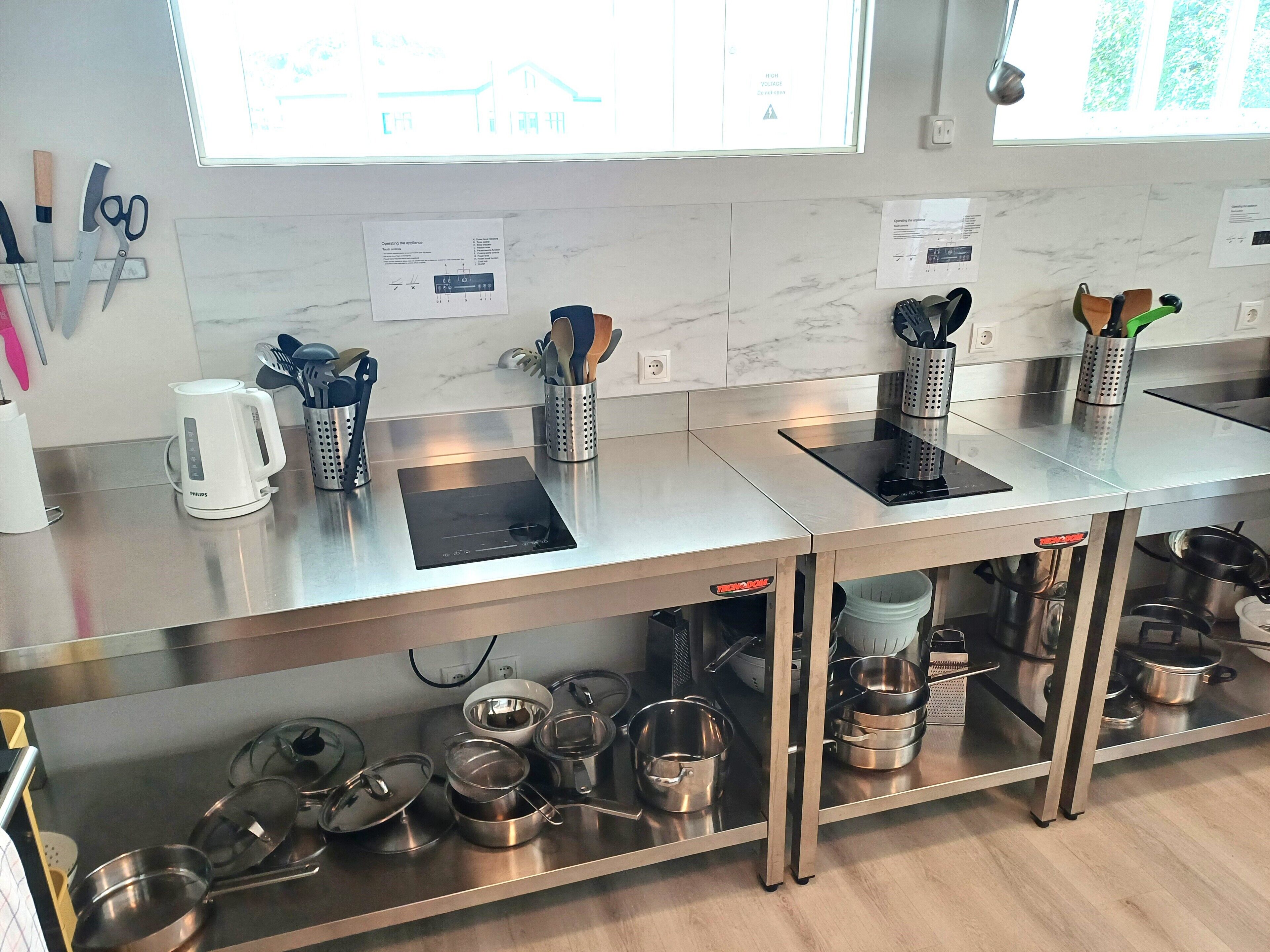 A modern kitchen with stainless steel countertops, a coffee maker, and various kitchen utensils.