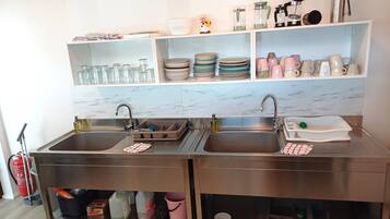 A modern kitchen with two sinks, a marble backsplash, and shelves with glassware and plates.