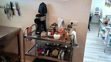 Un coin cuisine équipé d’une machine à café, d’ustensiles et d’un panneau invitant les clients à maintenir la propreté de la cuisine.