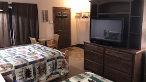 Un dormitorio con cama, cómoda, televisor y puerta.