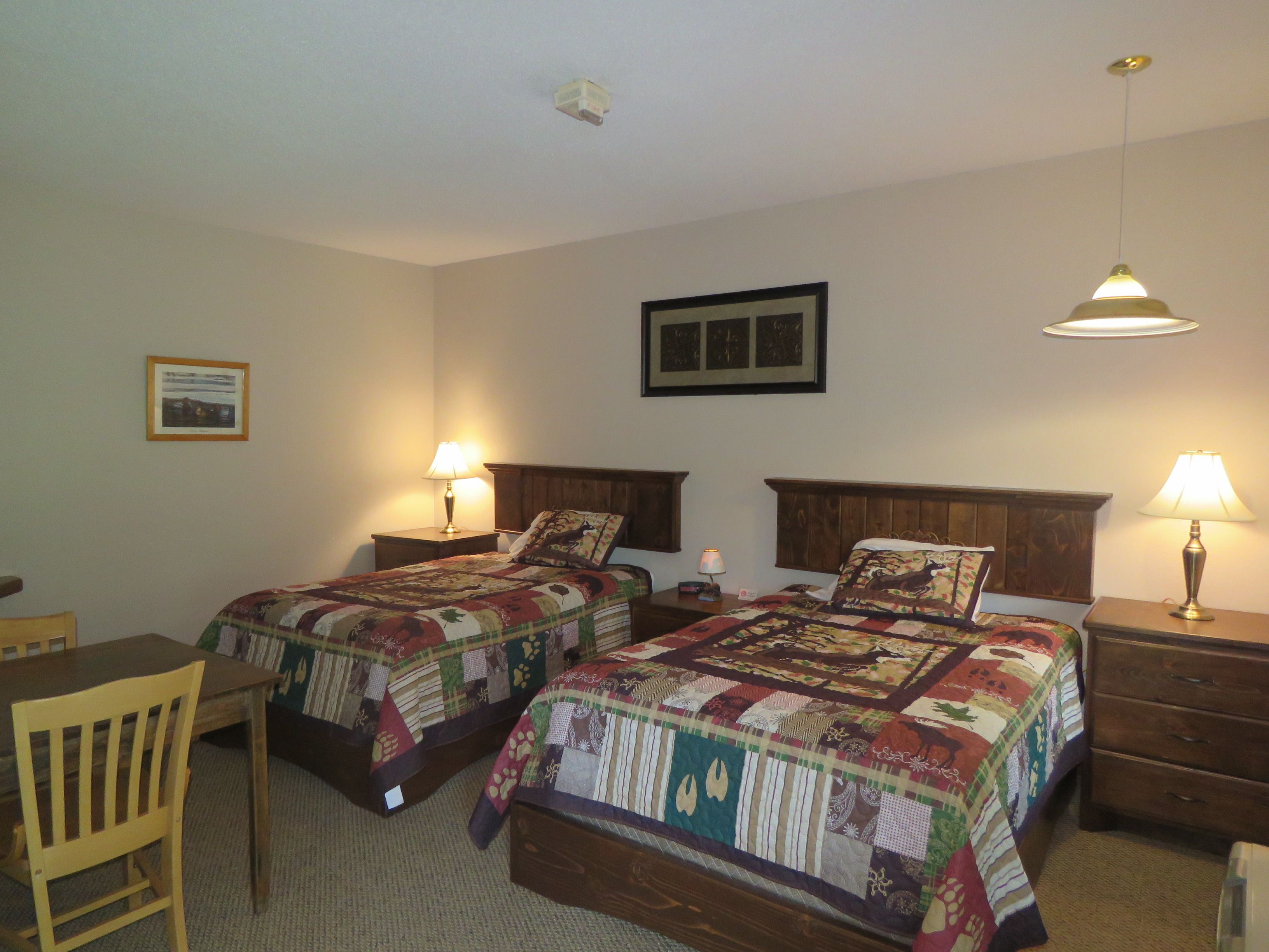A bedroom with two beds, a desk, a chair, and a dresser.