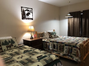 A hotel room with two beds, a nightstand with a lamp, a wall-mounted picture, and a window with curtains. - Tug Hill Resort (Redfield)