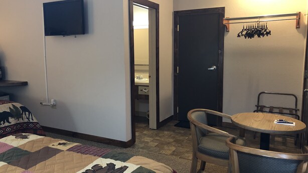 Habitación de hotel con cama, televisión, escritorio y silla, y una puerta que da a un baño.
