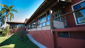 Un edificio de dos pisos con fachada roja, ventanas amplias y techo de tejas.