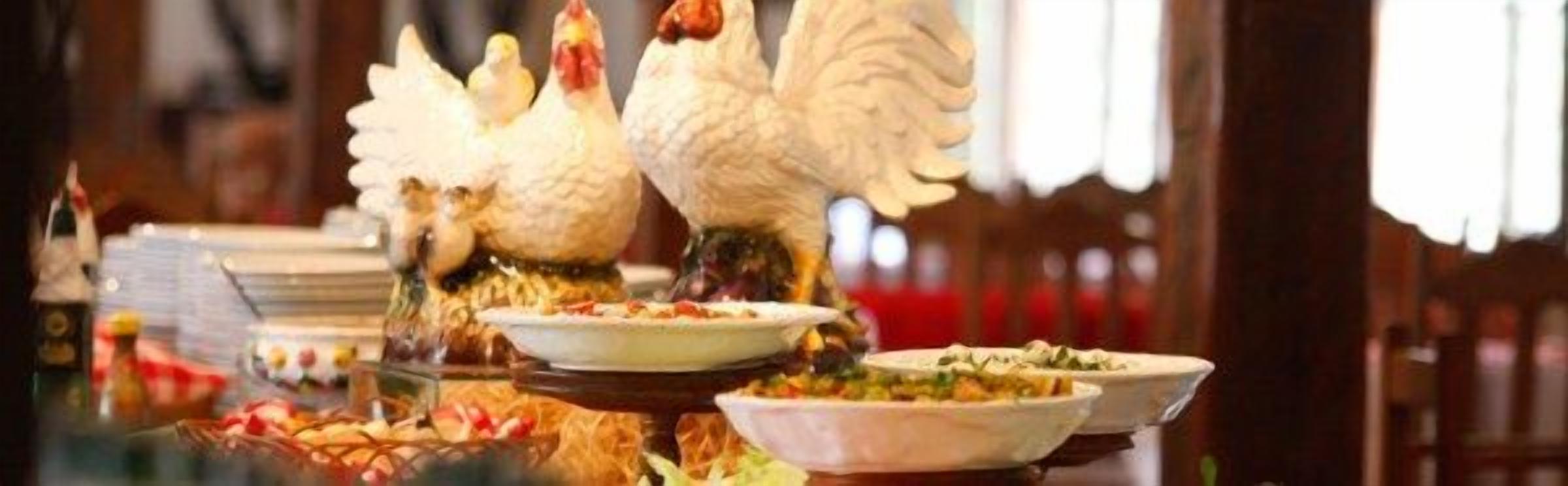 Une table à manger avec de nombreux plats et une figurine de poulet décorative.