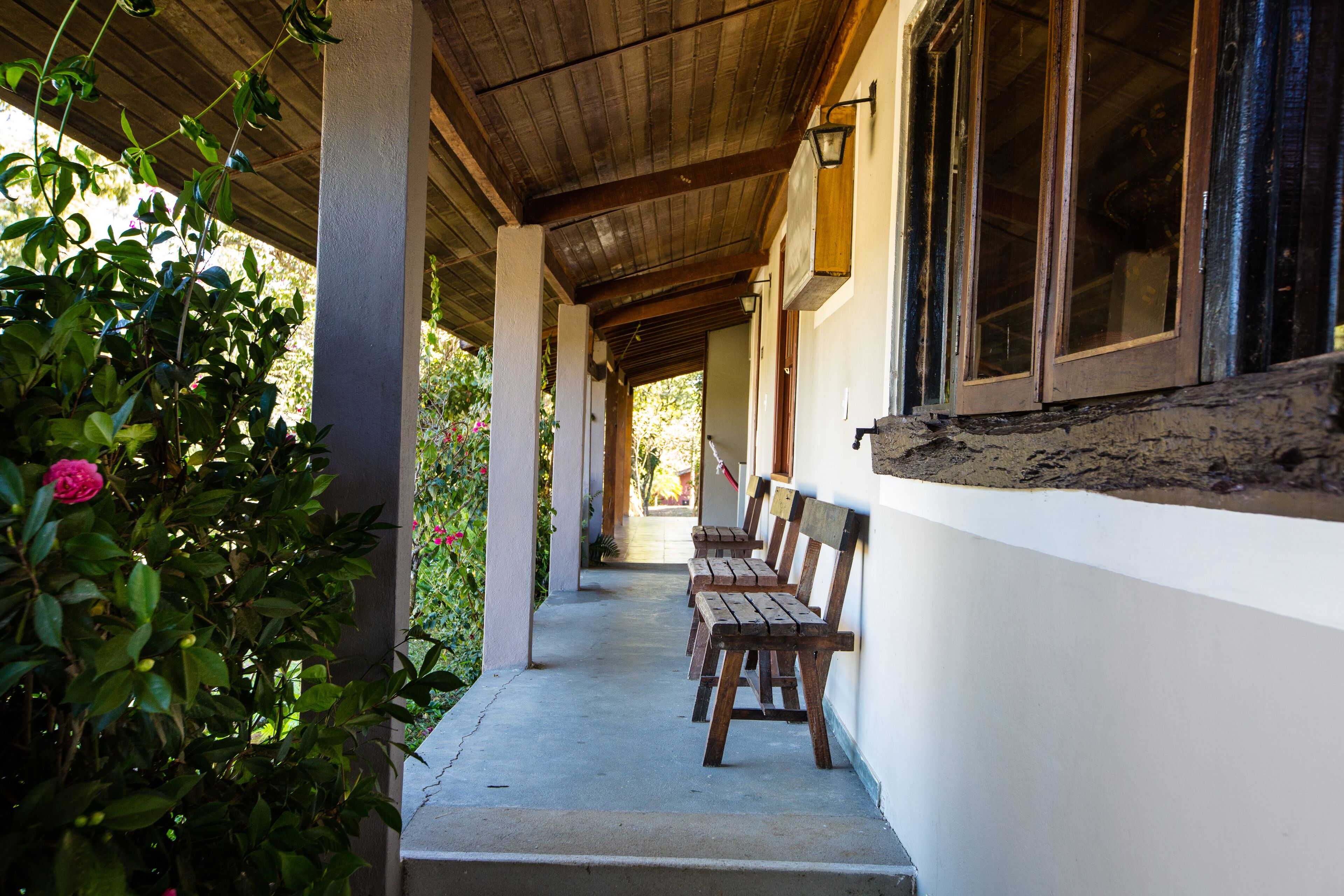 A covered outdoor seating area with wooden benches and a concrete floor.