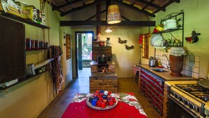 Una cocina rústica con un horno de ladrillo, estantes de madera y un mantel rojo.