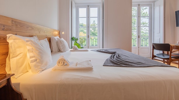 A hotel room with a bed, a chair, a table, and a balcony with a view. - Pendoa sintra collection (Sintra)