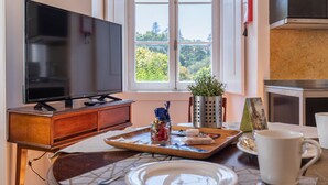 A modern kitchen with a large TV, a window with a view of greenery, and a tray with snacks. - Pendoa sintra collection (Sintra)