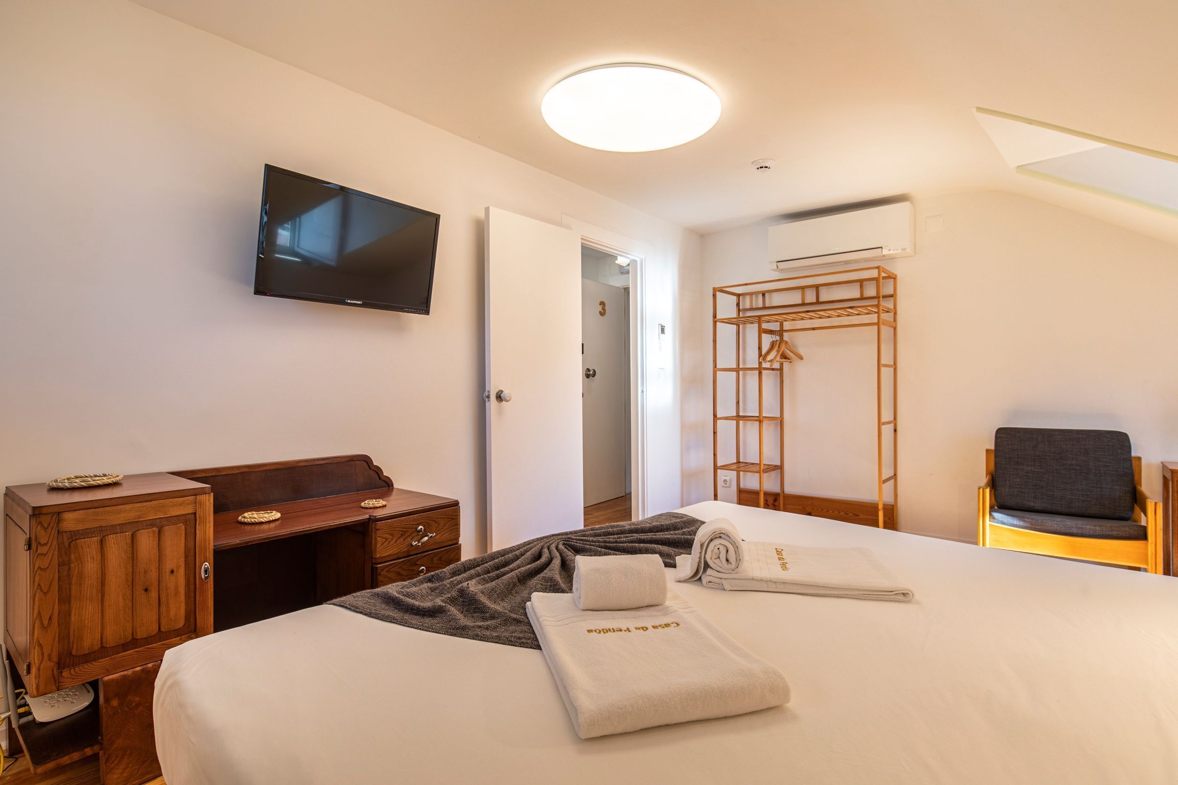 A hotel room with a bed, a desk, a TV, a wardrobe, and a chair.