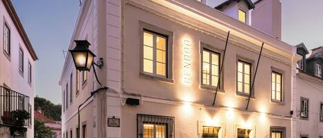 A historic building with a sign reading 'PENDORA' on the facade, a cobblestone street, and a traditional street lamp.