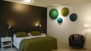 Een moderne slaapkamer met een bed, nachtkastjes, een stoel en wanddecoraties.
